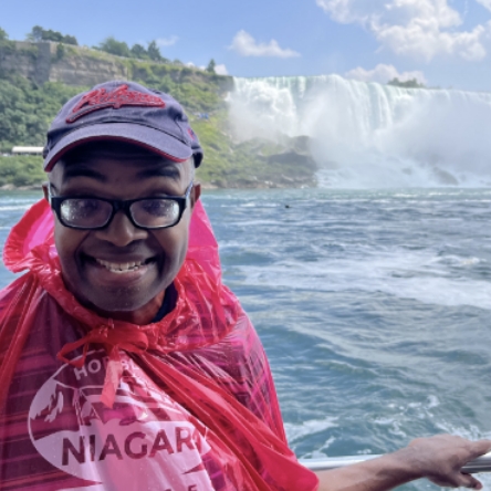 A person with intellectual and developmental disabilities (IDD) standing with Niagara Falls in the background.